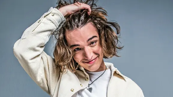 eros atomus fährt sich durch die Haare und lächelt