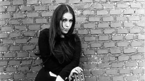 Massiel lehnt an einer Steinmauer. Schwarz-Weiß-Foto