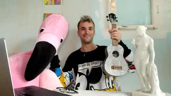 Deutschlands ESC-Künstler Jendrik mit einem Flamingo und einer Ukulele in seinem Zimmer.