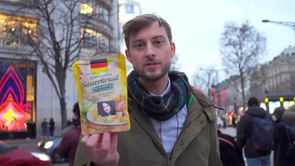 Consi mit einer Packung Sauerkraut in der Hand auf der Champs Élysées.